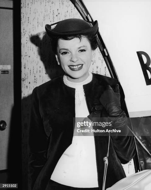 American actor and singer Judy Garland smiles and boards a plane en route to London to attend the premiere of her film, 'I Could Go on Singing',...