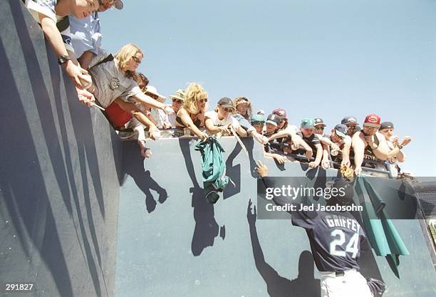 Outfielder Ken Griffey Jr. Of the Seattle Mariners gives high fives to fans during a preseason game against the Chicago Cubs at the Peoria Sports...