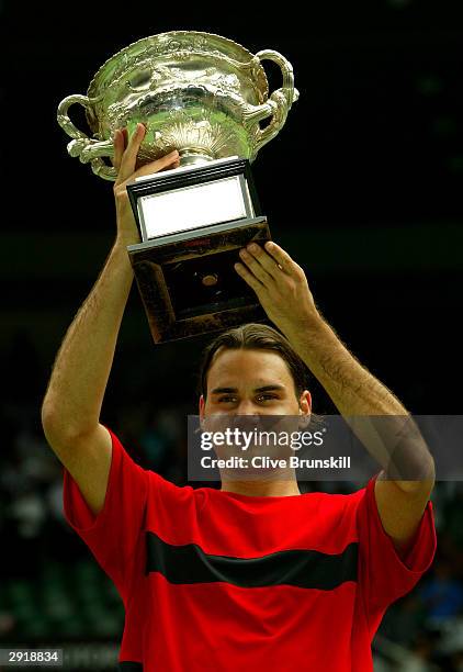 Roger Federer of Switzerland holds up the Australian Open Trophy after victory against Marat Safin of Russia during the Mens Singles Final during day...