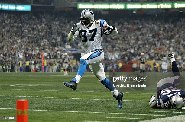 Receiver Muhsin Muhammad of the Carolina Panthers scores on an 85 yard touchdown reception as Eugene Wilson of the New England Patriots falls down in...