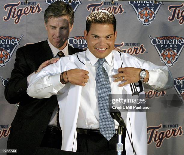 Detroit Tigers' General Manager and team President David Dombrowski helps Ivan "Pudge" Rodriguez put on his new Detroit Tigers uniform on February 1,...