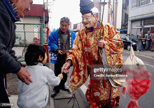 Man, dressed as the god, Ebisu, greets pedestrians in the area of Kamikagemori as part of the celebrations for Setsubun or the end of winter,...