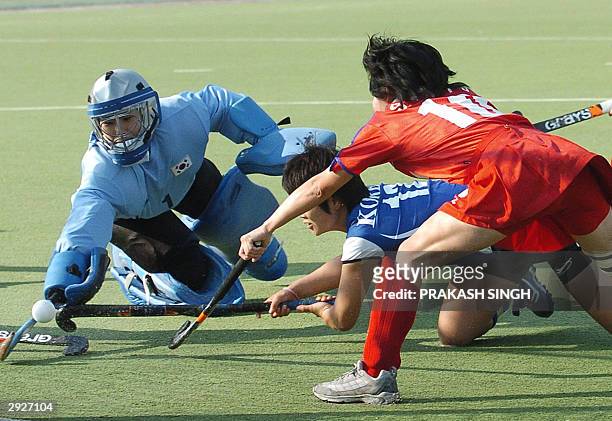 Korean hockey goalkeeper Moon Young Hui dives to save the goal with Oh Sun Soon as Japanese player Saito Naoko looks on during a league match of the...