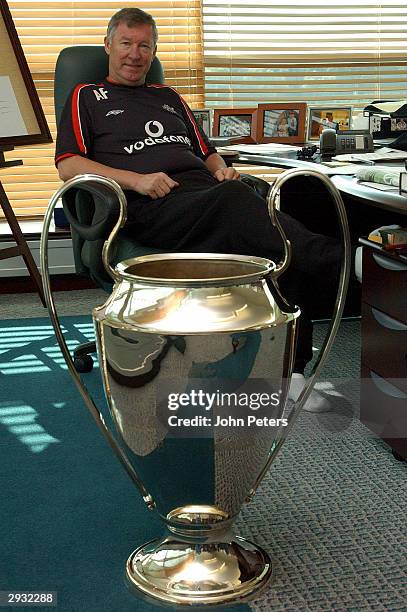 Sir Alex Ferguson poses at his desk at the Carrington training ground with the European Cup in the foreground on March 1, 2002.