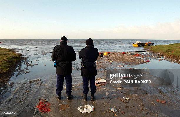 Two policemen stand 06 February 2004 on the edge of Morecambe Bay, where eighteen people thought to be Chinese workers digging for shellfish on...