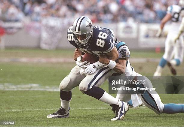 Tight end Eric Bjornson of the Dallas Cowboys gets tackled by Carolina Panthers defensive back Eric Davis during a playoff game at Ericsson Stadium...