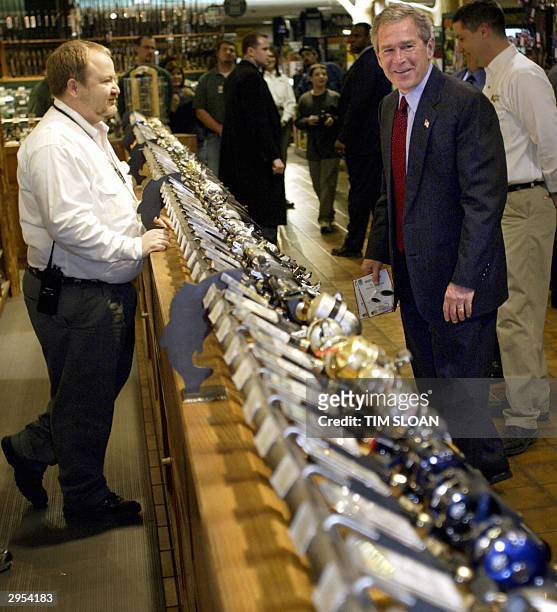 President George W. Bush looks at a fishing reel display during an unscheduled visit to the Bass Pro Shops Outdoor World store where he pressed the...