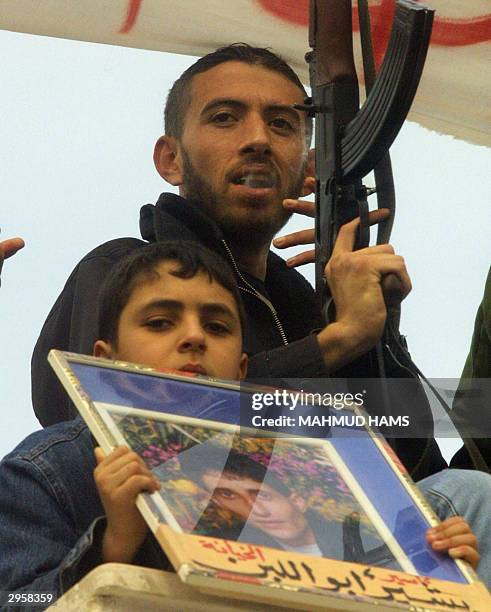 Palestinian boy holds a picture of Bashir Abu Laban, a member of the Popular Resistance Committees who was arrested along with three others for the...