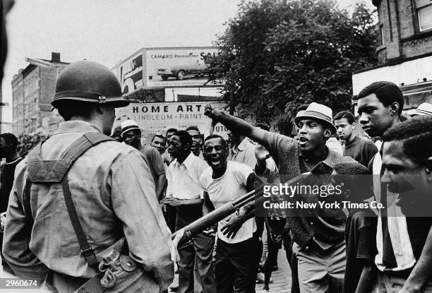 Black man gestures with his thumb down to an armed National Guardman, during a protest in the Newark race riots, Newark, New Jersey, July 14, 1967.