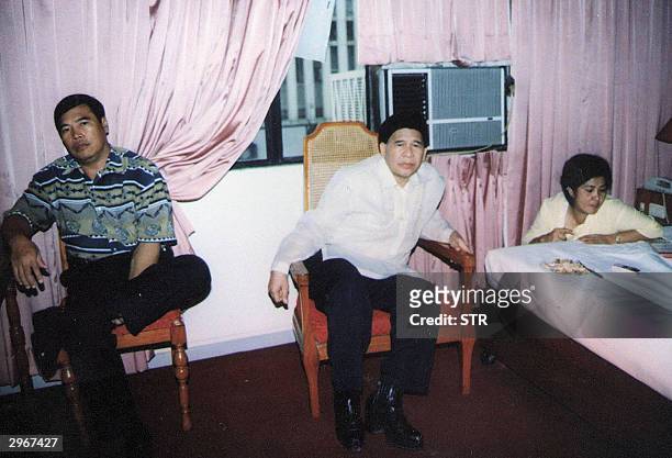 Philippine presidential candidate Eddie Gil accompanied by a bodyguard and a female aide sits inside his hotel room in southern Cagayan de Oro city...