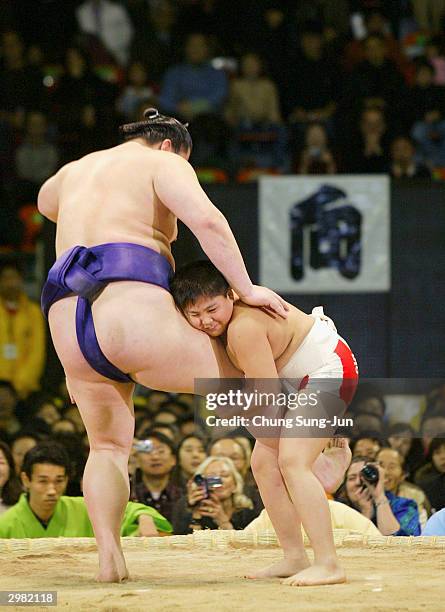 Japanese sumo wrestler plays with children before the opening ceremony of a sumo tournament at the Changchung gymnasium on February 14 in Seoul,...