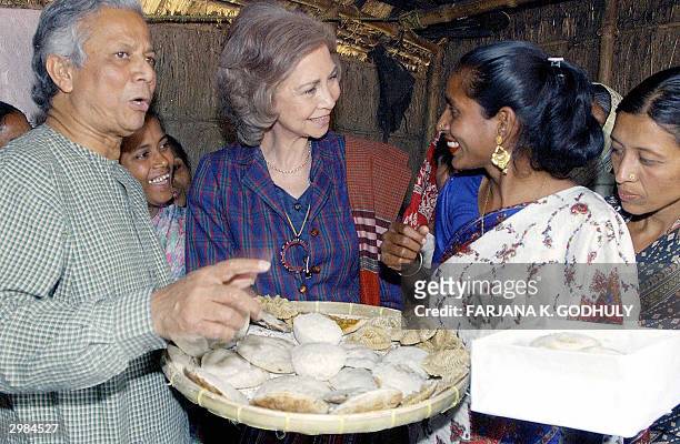 Queen Sofia of Spain is offered traditional cakes by a Bangladeshi woman during her visit at a Microcredit project site in Comilla, some 80...