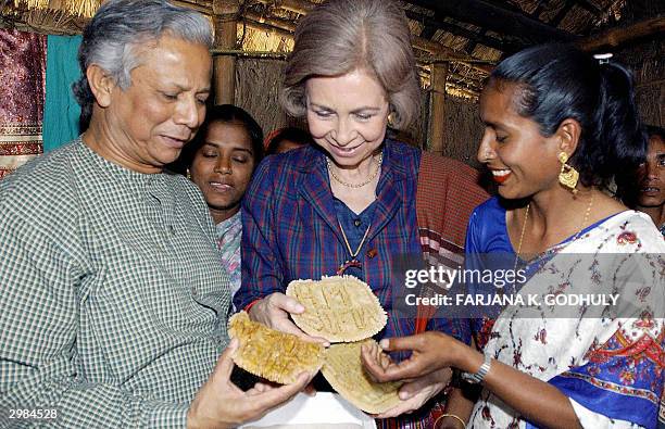 Queen Sofia of Spain is offered traditional cakes by a Bangladeshi woman during her visit at a Microcredit project site in Comilla, some 80...