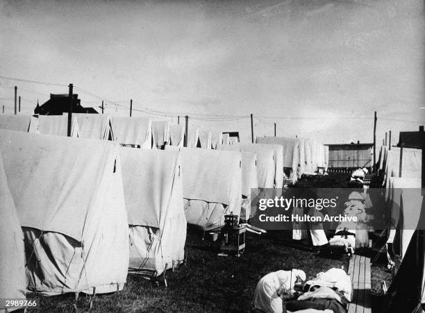 Nurses care for victims of a Spanish influenza epidemic outdoors amidst canvas tents during an outdoor fresh air cure, Lawrence, Massachusetts, 1918