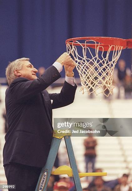 Coach Dean Smith of the North Carolina Tarheels cuts the net after a playoff game against the Louisville Cardinals at the Carrier Dome in Syracuse,...