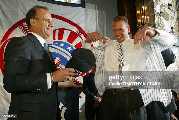 Alex Rodriguez puts on a New York Yankees jersey while Yankee Manager Joe Torre holds a Yankee cap 7 February during a press conference at Yankee...