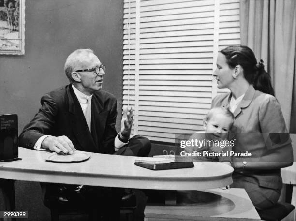 American pediatrician Dr Benjamin Spock talks to a mother holding a baby, September 16, 1955.