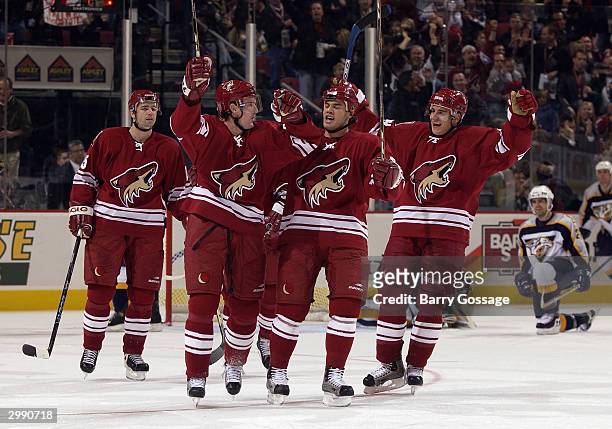 Radoslav Suchy of the Phoenix Coyotes, background, looks on as teammates Brian Savage, David Tanabe and Branko Radivojevic celebrate a goal against...