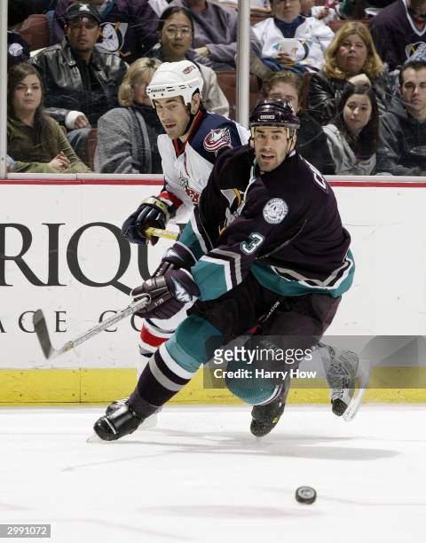 Keith Carney of the Mighty Ducks of Anaheim looks to the puck as Geoff Sanderson of the Columbus Blue Jackets hooks Carney during the game on January...