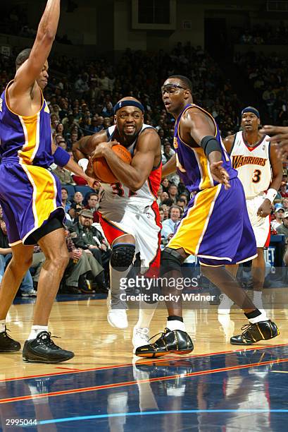 Nick Van Exel of the Golden State Warriors drives the ball through Deavan George and Horace Grant of the Los Angeles Lakers on February 18, 2004 at...