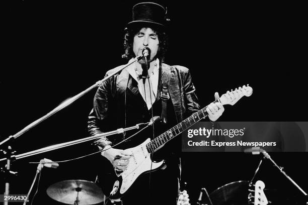 American singer and songwriter Bob Dylan sings and plays guitar on stage, wearing a top hat, during the Blackbushe Pop Festival, Hampshire, England,...