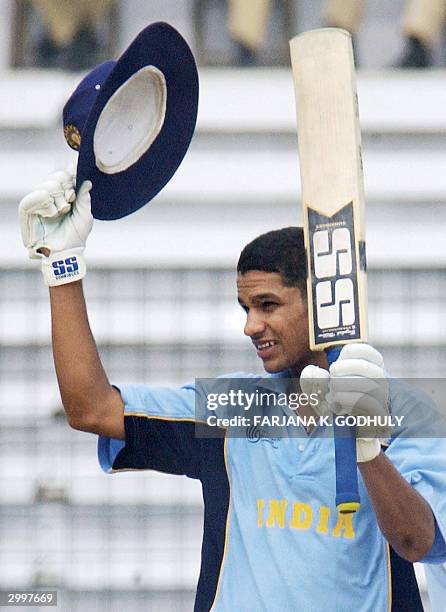 Indian U19 cricketer Shikhar Dhawan raises his bat and floppy hat to an unseen crowd after reaching his century during a match of The Under-19 World...