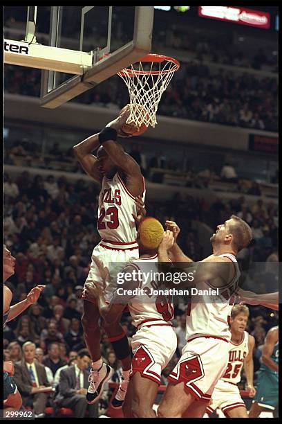 Guard Michael Jordan of the Chicago Bulls pulls down the rebound from a shot by the Charlotte Hornets above teammates Dennis Rodman and center Bill...