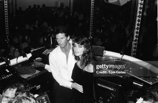 American fashion designer Calvin Klein and model and actor Brooke Shields stand in the DJ booth at the reopening of Studio 54 nightclub, New York...