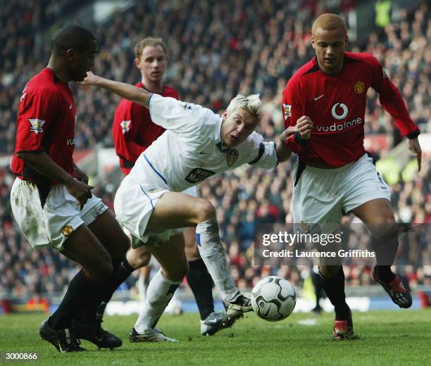 Alan Smith of Leeds clashes with Wes Brown and Quinton Fortune of Man Utd during the FA Barclaycard Premiership match between Manchester United and...