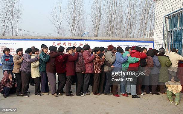 Group of Chinese farmers queue up at a local clinic in Wenlou village, China's Henan province 21 February 2004, to get their supply of free AIDS...