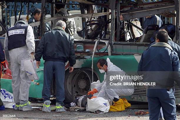 Policeman inspects a body in front of the exploded bus after a Palestinian suicide attack on an Israeli bus in the center of Jerusalem 22 February...