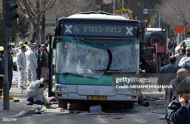 Israeli policemen inspect the exploded bus that was attacked by a Palestinian suicide bomber in the center of Jerusalem 22 February 2004. A suicide...