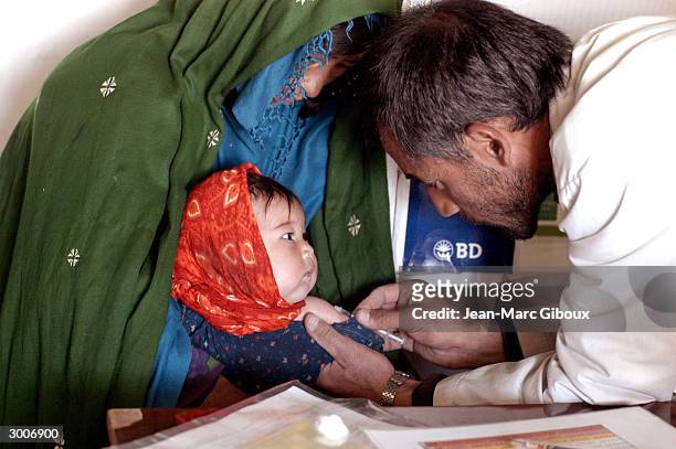 An Afghan nurse immunizes a child November 17, 2003 at the Medecins Sans Frontieres clinic in Sariqol, high in the mountains of Bamiyan Province of...