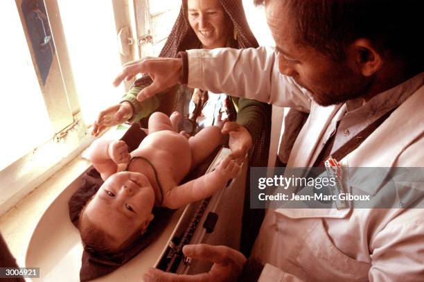Medecins Sans Frontieres nurse Abdul Majid weighs a healthy looking Hazara baby during an exam November 17, 2003 at the MSF clinic in Sariqol, high...