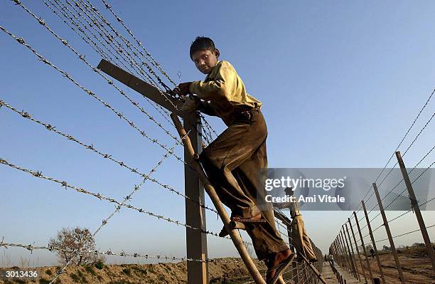 Indian labourers build a fence separating India and Pakistan along the International Border on February 25, 2004 near Ahknoor, India. With the recent...