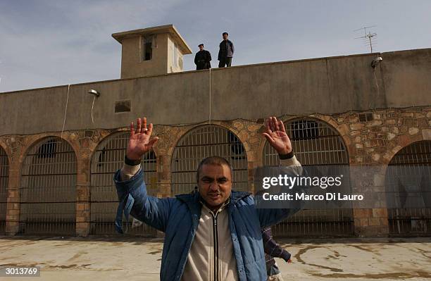 An Iraqi mentally insane patient raises his hands in the prison courtyard February 25, 2004 in the Kurdish town of Arbil, 220 miles north of Baghdad....