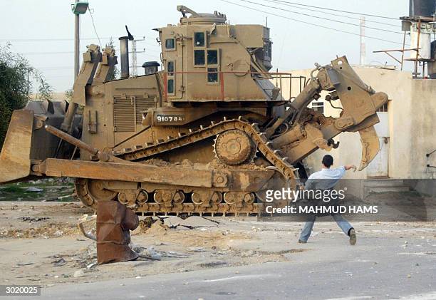 Palestinian boy throws stones at an Israeli bulldozer in front of the industrial zone at Erez crossing 27 February 2004. The Israeli army said it had...