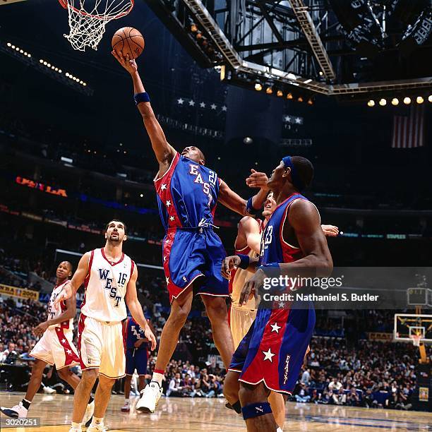 Jamaal Magloire of the Eastern Conference All-Stars shoots against Dirk Nowitzki and Peja Stojakovic of the Western Conference All-Stars during the...