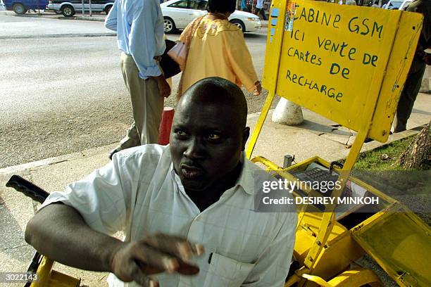 Disabled Gabonese sits 28 February 2004 in his wheelchair, which is equipped with a GSM telephone at the back, in the capital Libreville. Some 20...