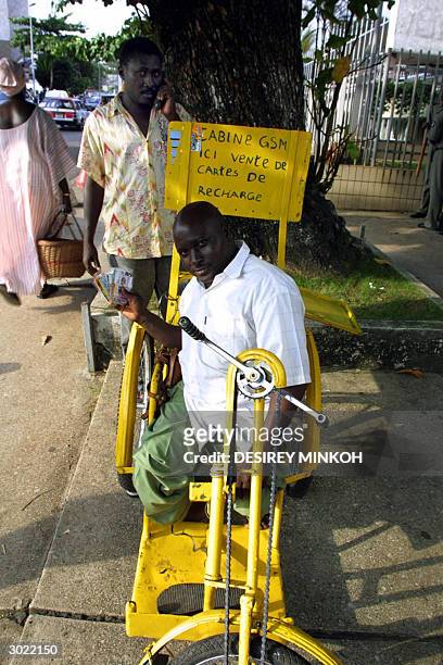 Disabled Gabonese sits 28 February 2004 in his wheelchair, which is equipped with a GSM telephone at the back, in the capital Libreville. Some 20...