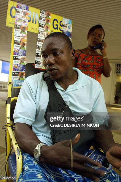 Disabled Gabonese sits 28 February 2004 in his wheelchair, which is equipped with a GSM telephone at the back, in the capital Libreville. Some 20...