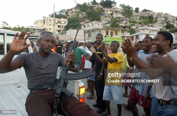 Haitians who live in a slum in the Canape Vert district of Port-au-Prince cheer a rebel belonging to the Liberation Front of the Haitian Armed Forces...