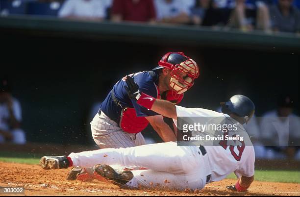 Infielder John Valentin of the Boston Red Sox slides into home as catcher Terry Steinbach of the Minnesota Twins tries to tag him out during a spring...