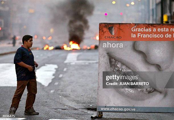 Boy walks near burning barricades that block a street in Caracas, during demonstrations against Venezuelan President Hugo Chavez, 02 March, 2004....