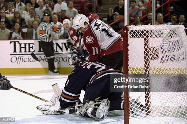 Right wing Keith Jones of the Colorado Avalanche and goaltender Curtis Joseph of the Edmonton Oilers in action during a playoff game at the McNichols...