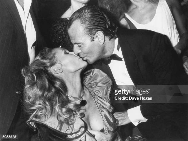Spanish singer Julio Iglesias kisses Swiss actress Ursula Andress during his 40th birthday party in Paris, 30th September 1983.
