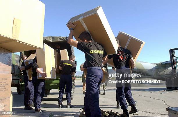 Newly arrived French Gendarmes of the Gendarmerie Mobile unit load some of their supplies and gear into a truck after arriving at Port-Au-Prince's...