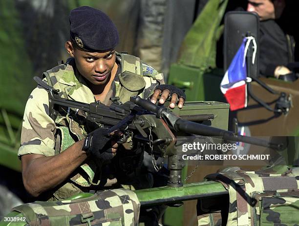 French soldier holds a high caliber machine gun mounted on the lead vehicle of a convoy leaving the city's airport, as they escorted newly arrived...