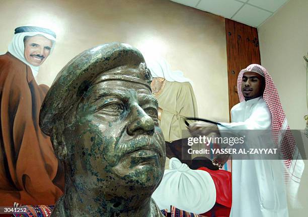 Kuwaiti man hits a bronze statue of the head of deposed Iraqi leader Saddam Hussein on display at Kuwait's Museum for National Works, a museum...