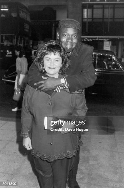 British comedian Lenny Henry puts his arms around his wife, comedienne Dawn French, who is holding a programme for 'Lenny Live and Unleashed', July...